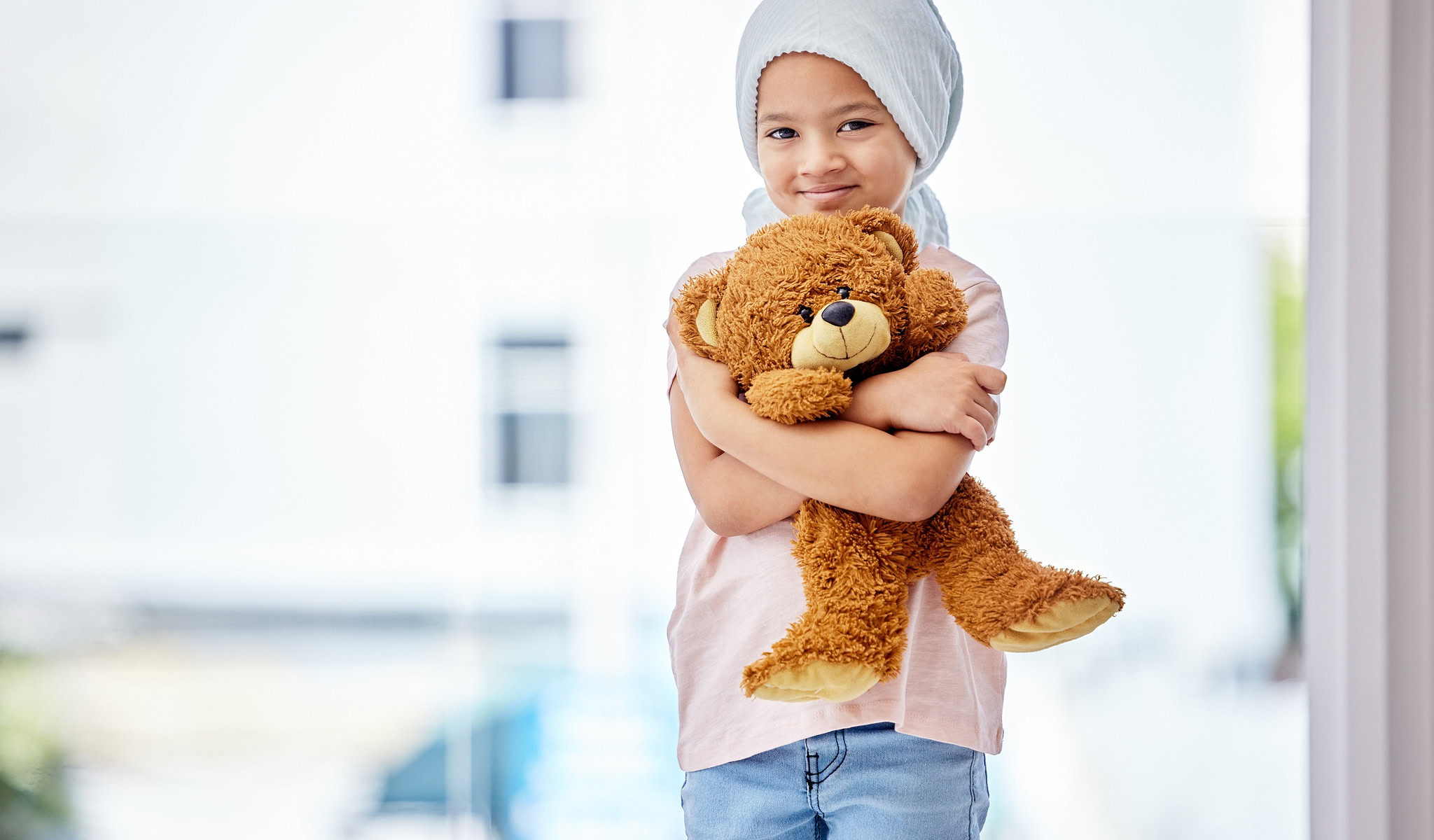 Shot of a little girl standing with her teddy in a clinic