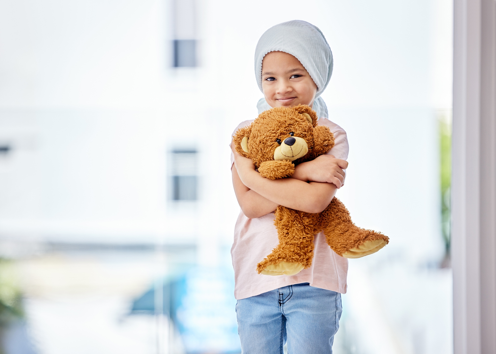 Shot of a little girl standing with her teddy in a clinic